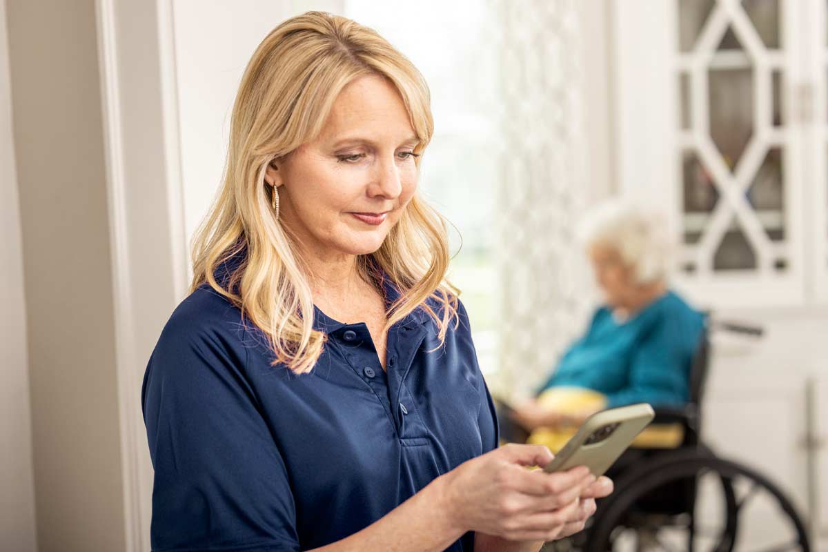 Care Professional reviews mobile app with senior woman